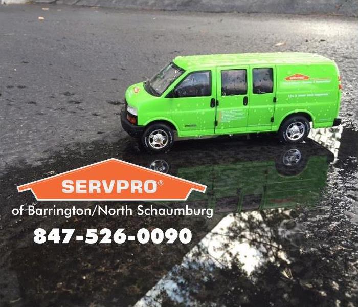 Green van with a SERVPRO logo on a black wet street.